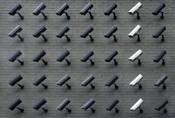 A grid of 35 surveillance cameras mounted on a wall and pointing to the lower left