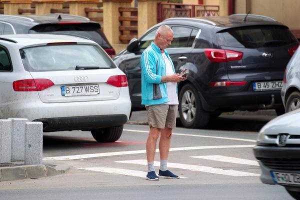 Man gazing at a phone while standing in traffic