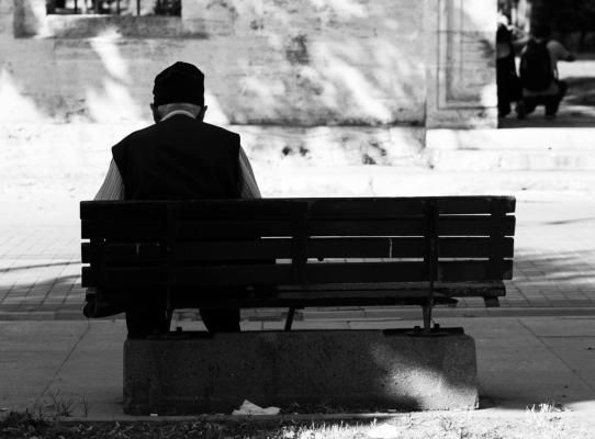 Elderly man sitting alone on a park bench
