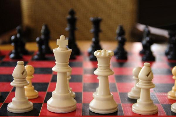 Close-up view of a chess board with pieces arranged on the red and black squares