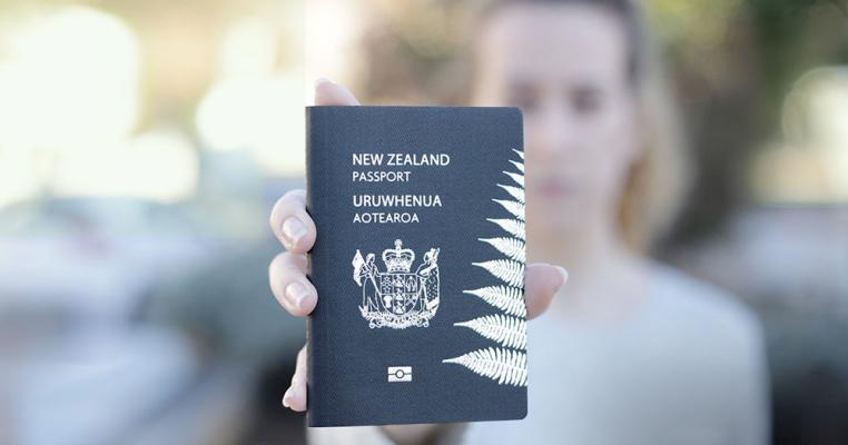 Woman holding a New Zealand passport in her outstretched hand
