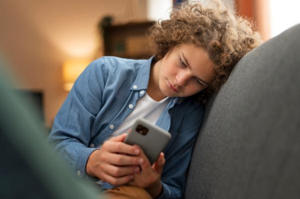 Teen boy peering at a cellphone