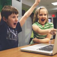 Children cheering at what's displayed on a laptop