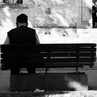 Elderly man sitting alone on a park bench