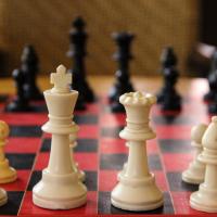 Close-up view of a chess board with pieces arranged on the red and black squares