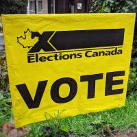 Yellow Elections Canada lawn sign that says 'vote' indicating a polling station for a federal election