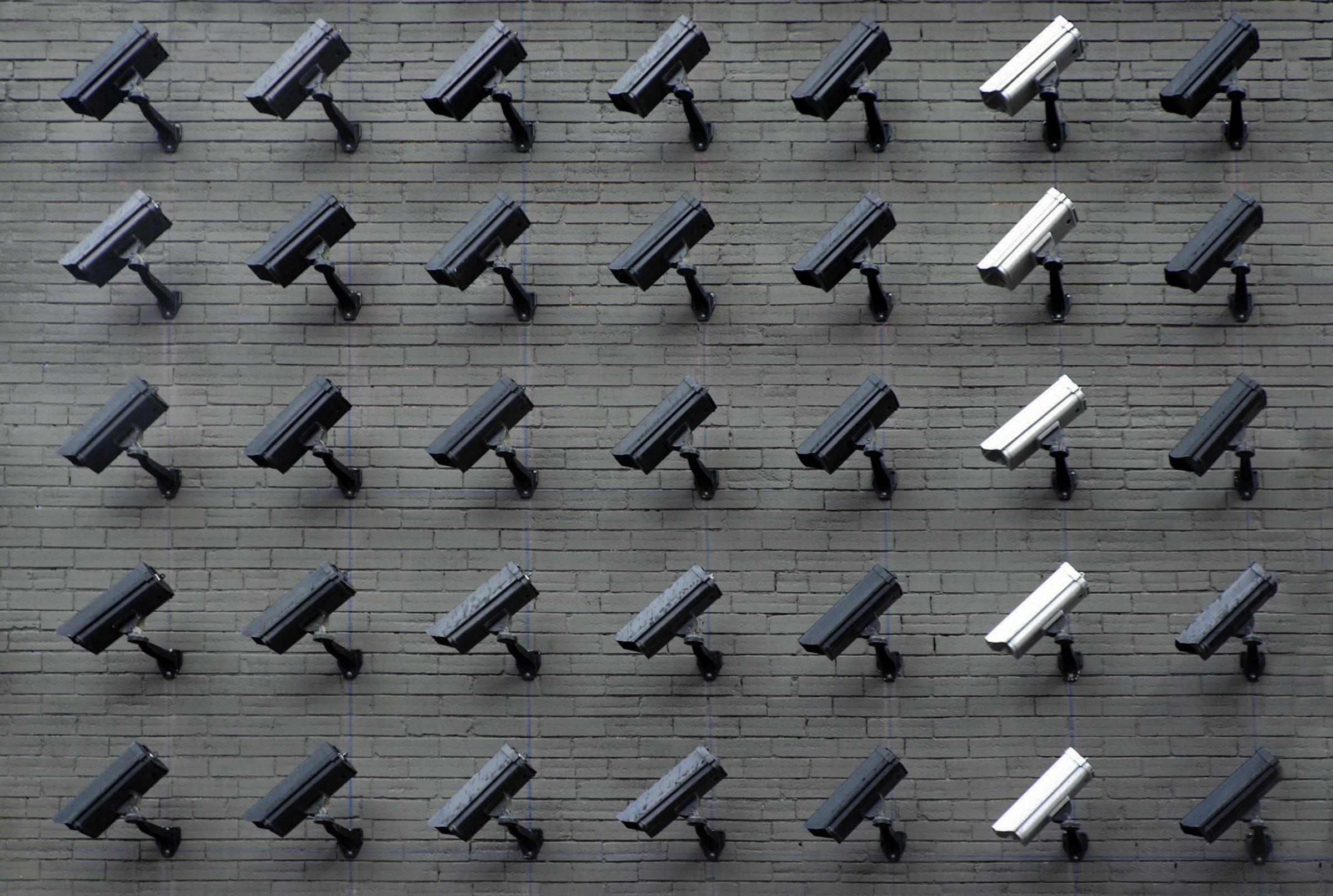A grid of 35 surveillance cameras mounted on a wall and pointing to the lower left