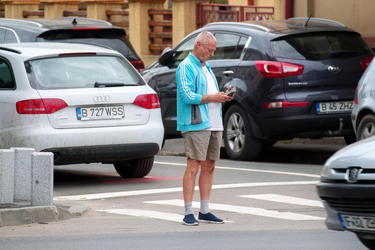 Man gazing at a phone while standing in traffic