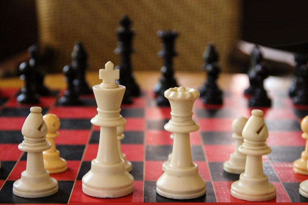 Close-up view of a chess board with pieces arranged on the red and black squares